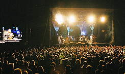 Bühne mit Band und Gebärdensprachedolmetscherin, übertragen auf Großleinwand links